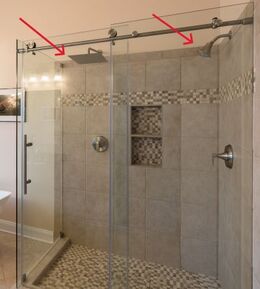 シャワーヘッドが二つ付いているタイルとガラス張りのゆったりしたシャワー室。