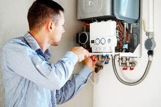 Technician repairing a tankless hot water heater tank on the wall.
