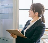 An Asian woman in suits checking the interior of a house with a clipboard and a pen.